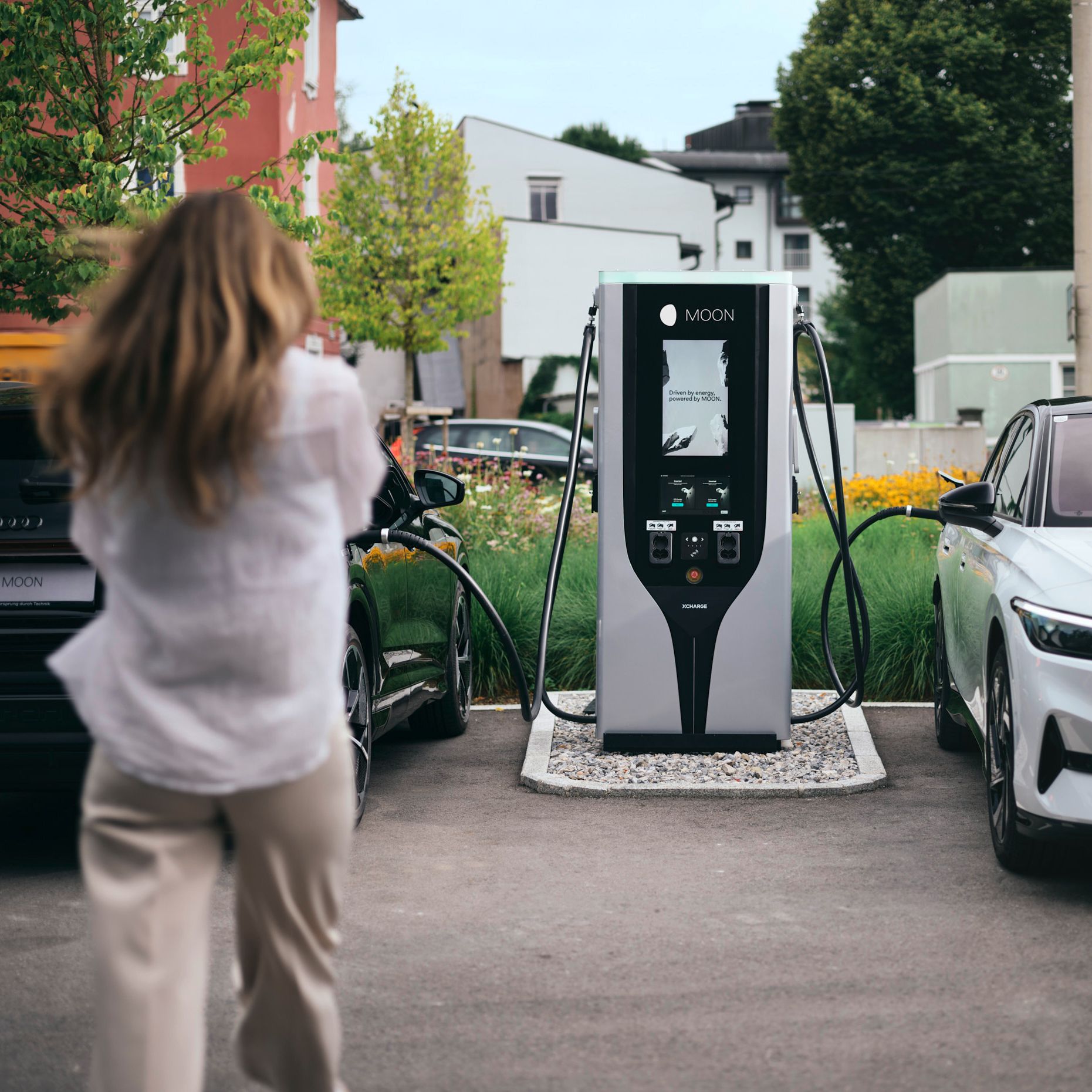 Person geht auf eine Schnellladestation zwischen zwei E-Autos zu