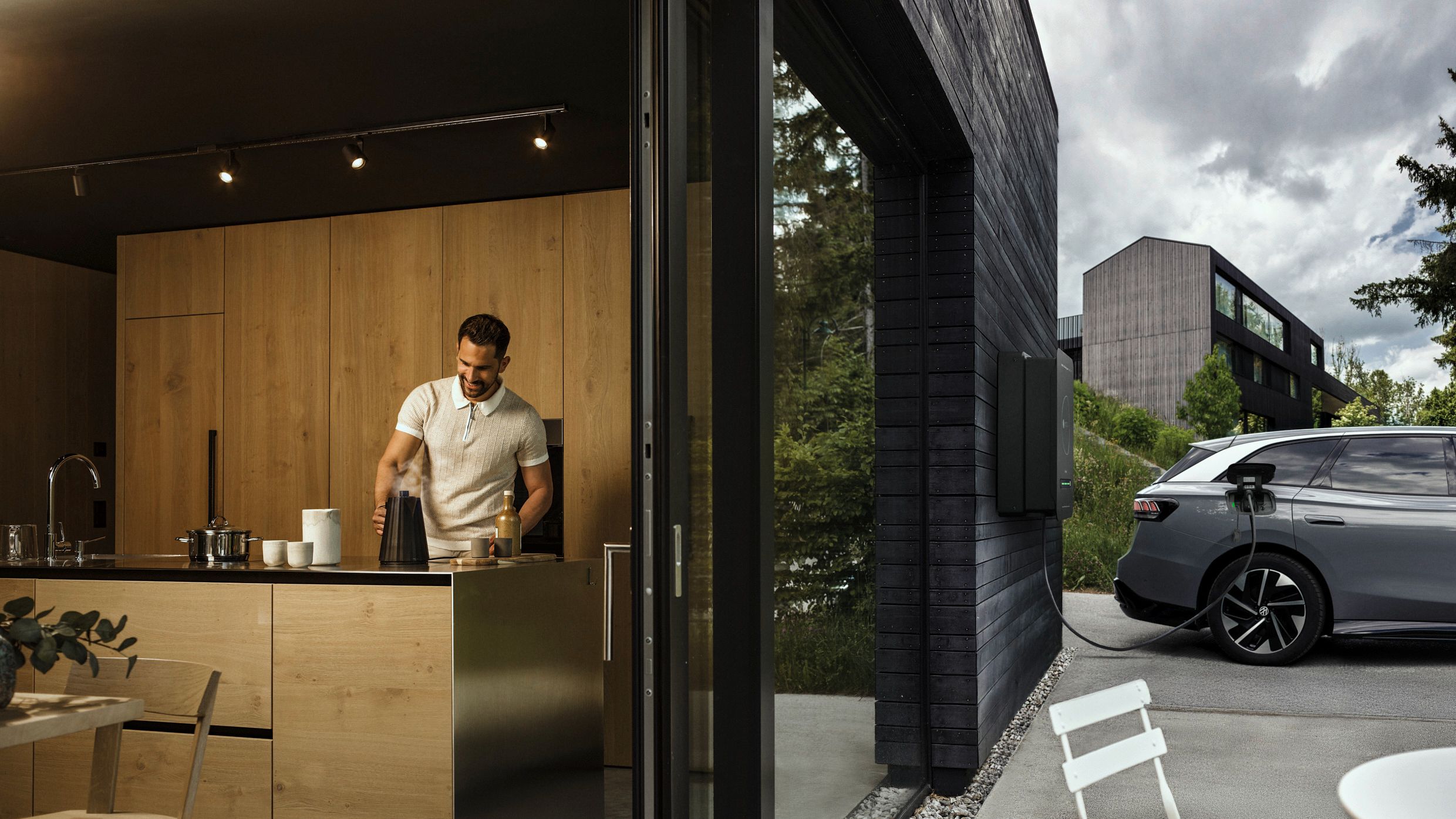 Mann in der Küche während Auto durch bidirektionale Wallbox Haus mit Strom versorgt