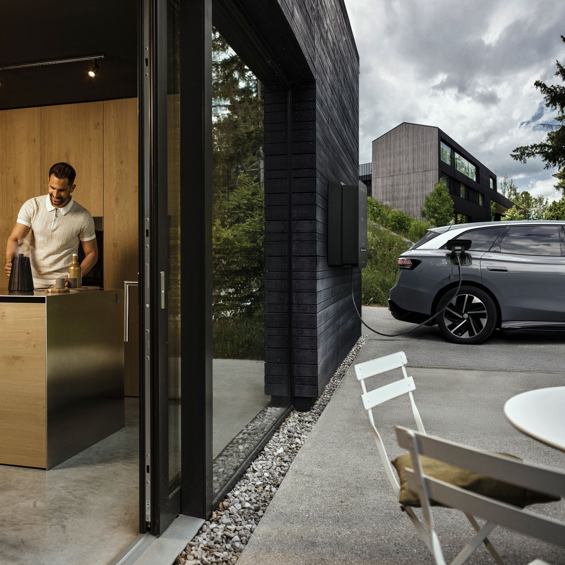 Mann in der Küche während Auto durch bidirektionale Wallbox Haus mit Strom versorgt