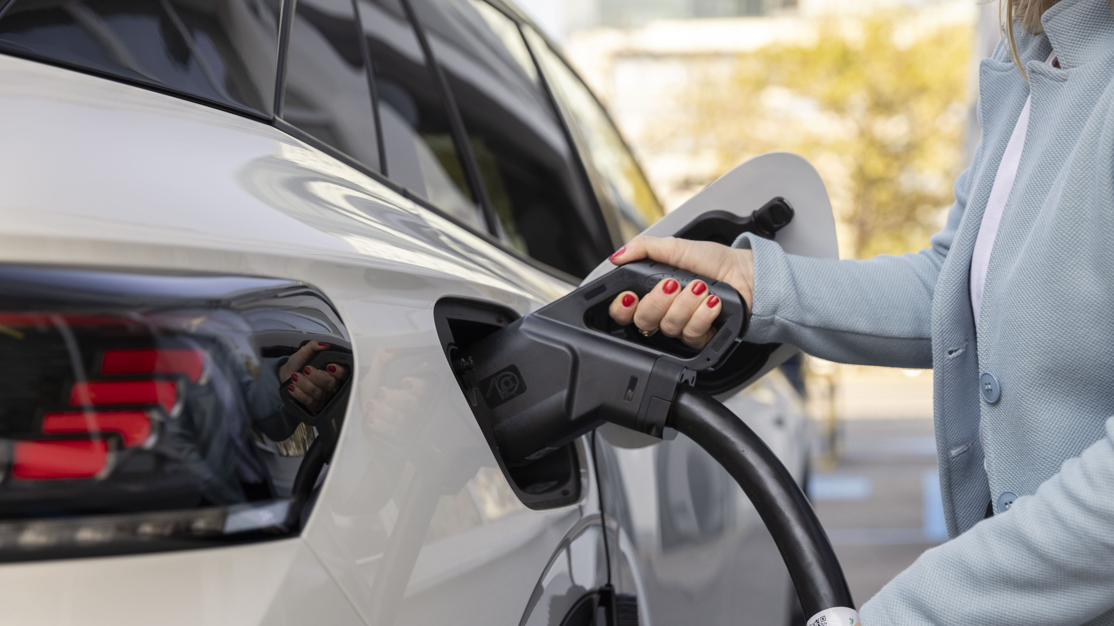 Frau steckt Ladekabel in ein Auto