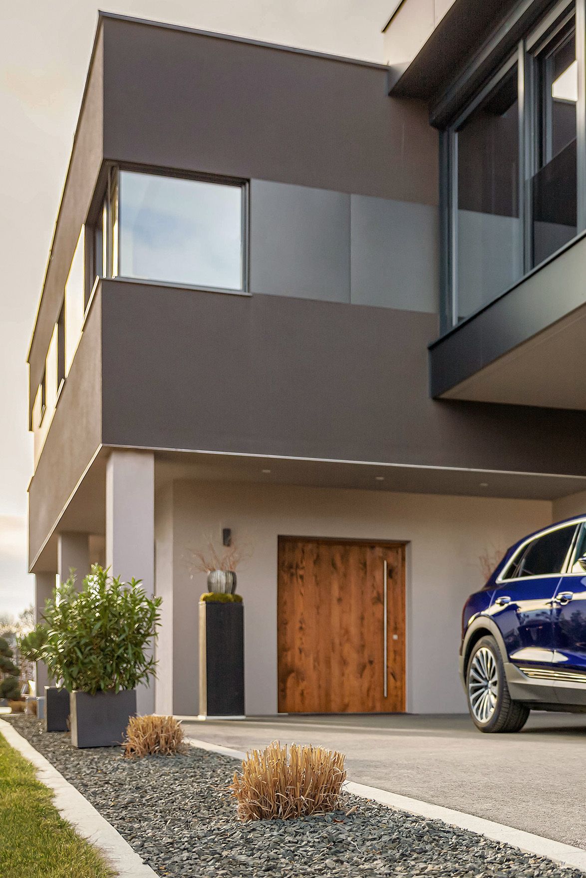 Mann geht mit einem Kabel in der Hand auf ein E-Auto bei einem Haus zu