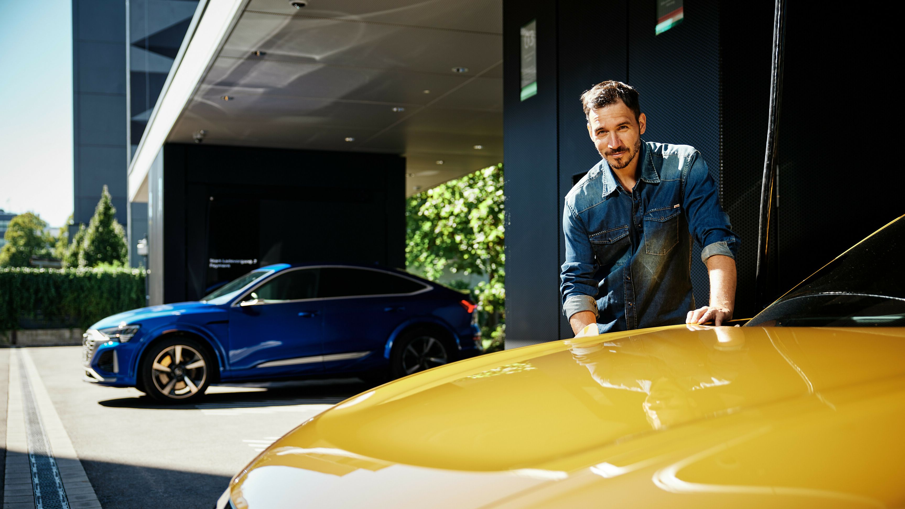 Mann lädt gelbes Auto an der Audi charging hub