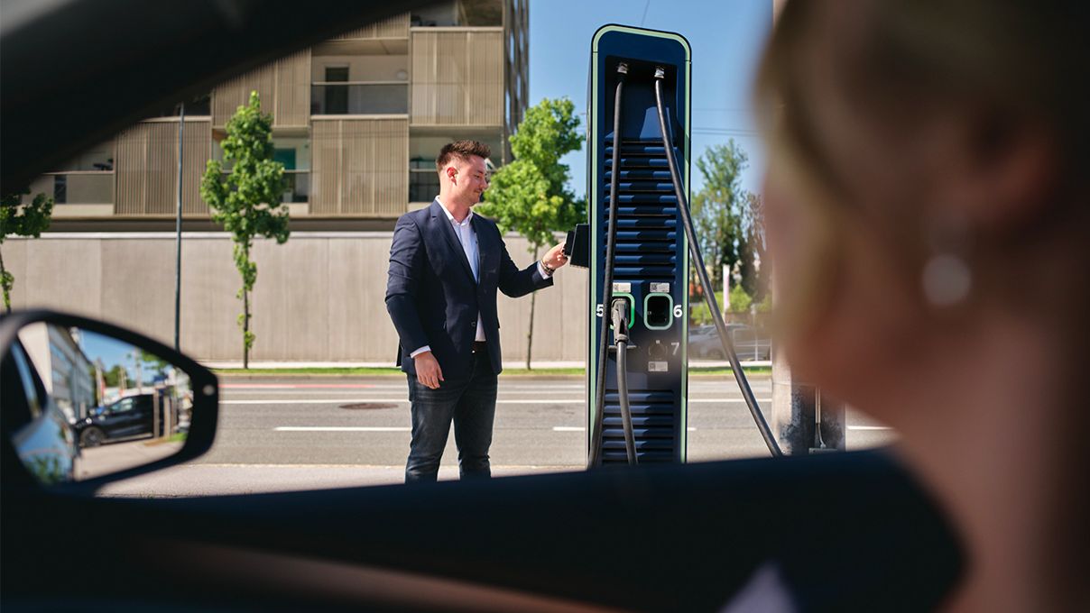 Mann hält Ladekarte an eine Schnellladestation