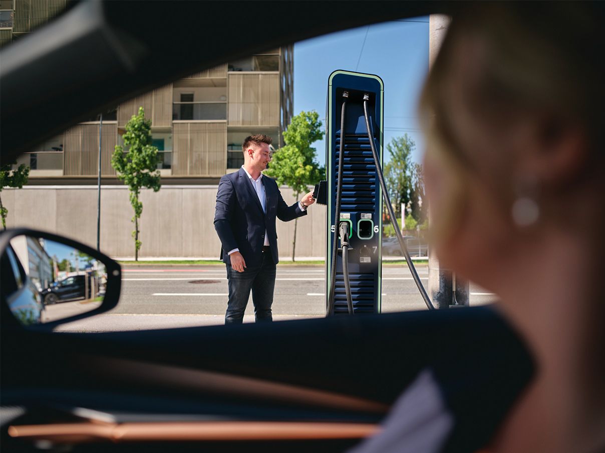 Mann hält Ladekarte an eine Schnellladestation