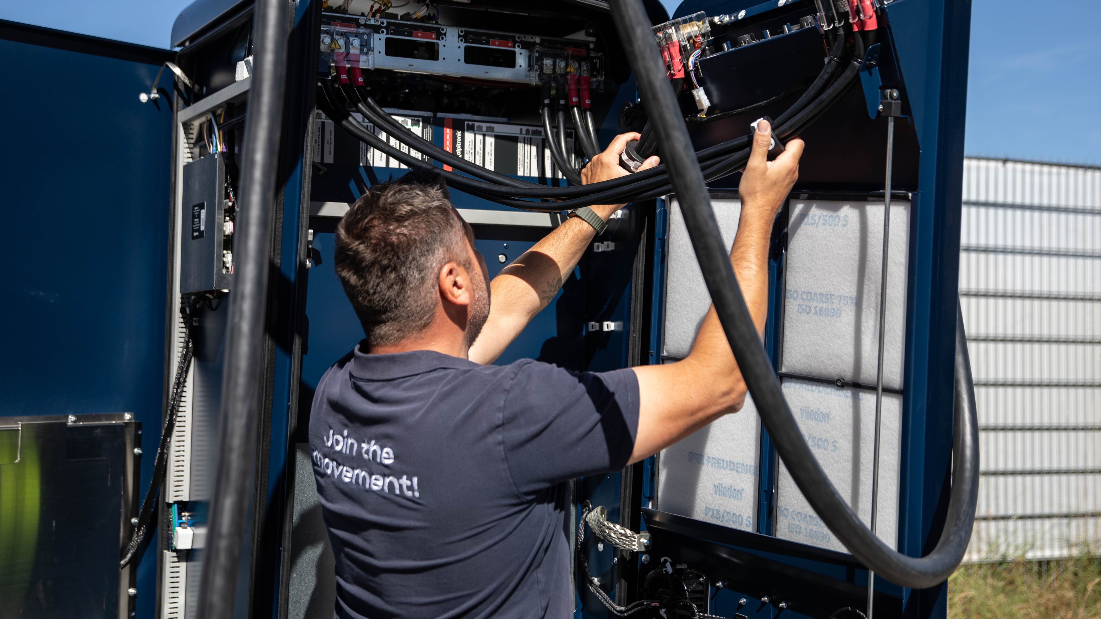 ein Mann arbeitet an dem Innenleben einer HYC 200-400 Schnellladestation