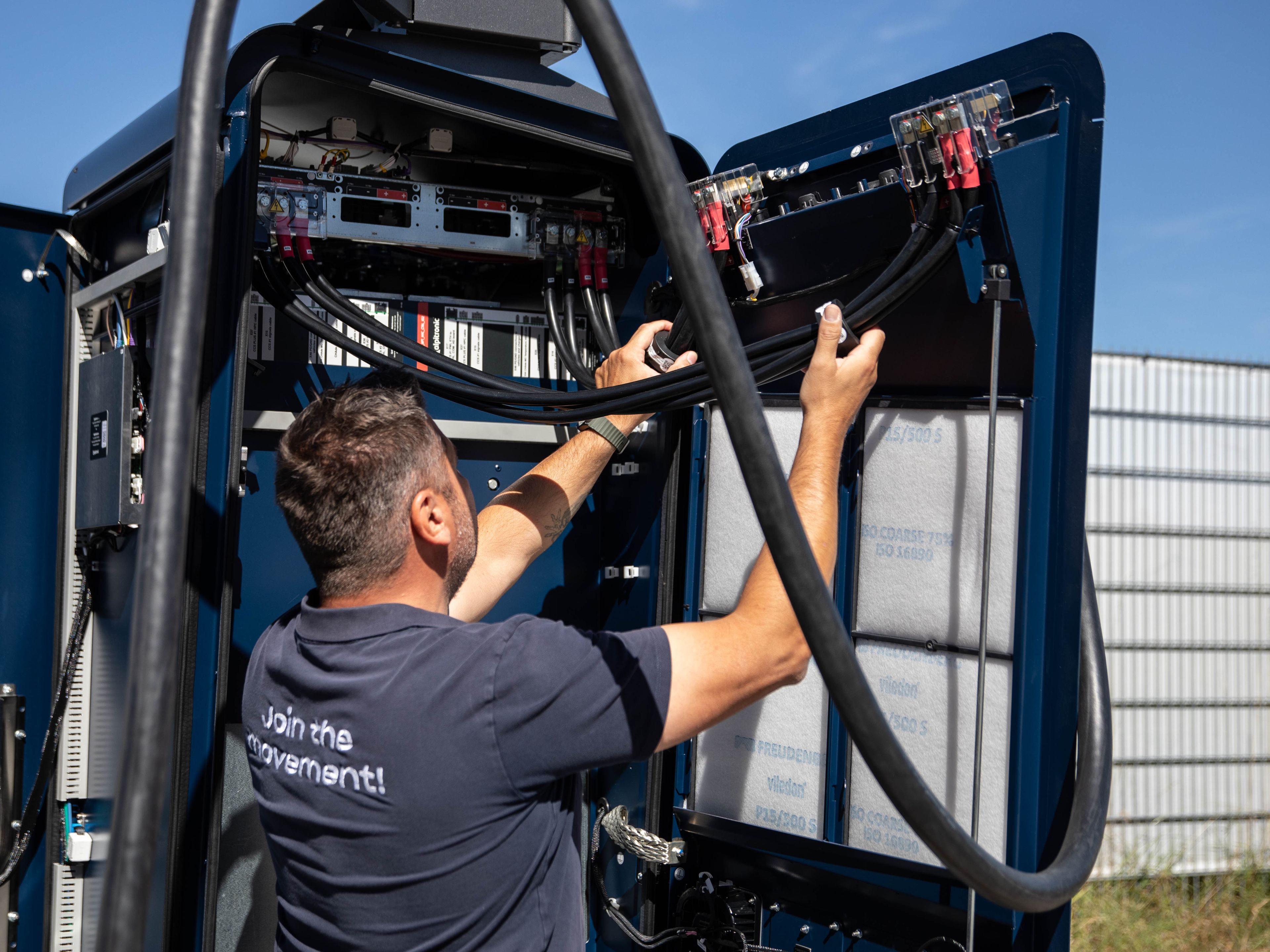 ein Mann arbeitet an dem Innenleben einer HYC 200-400 Schnellladestation