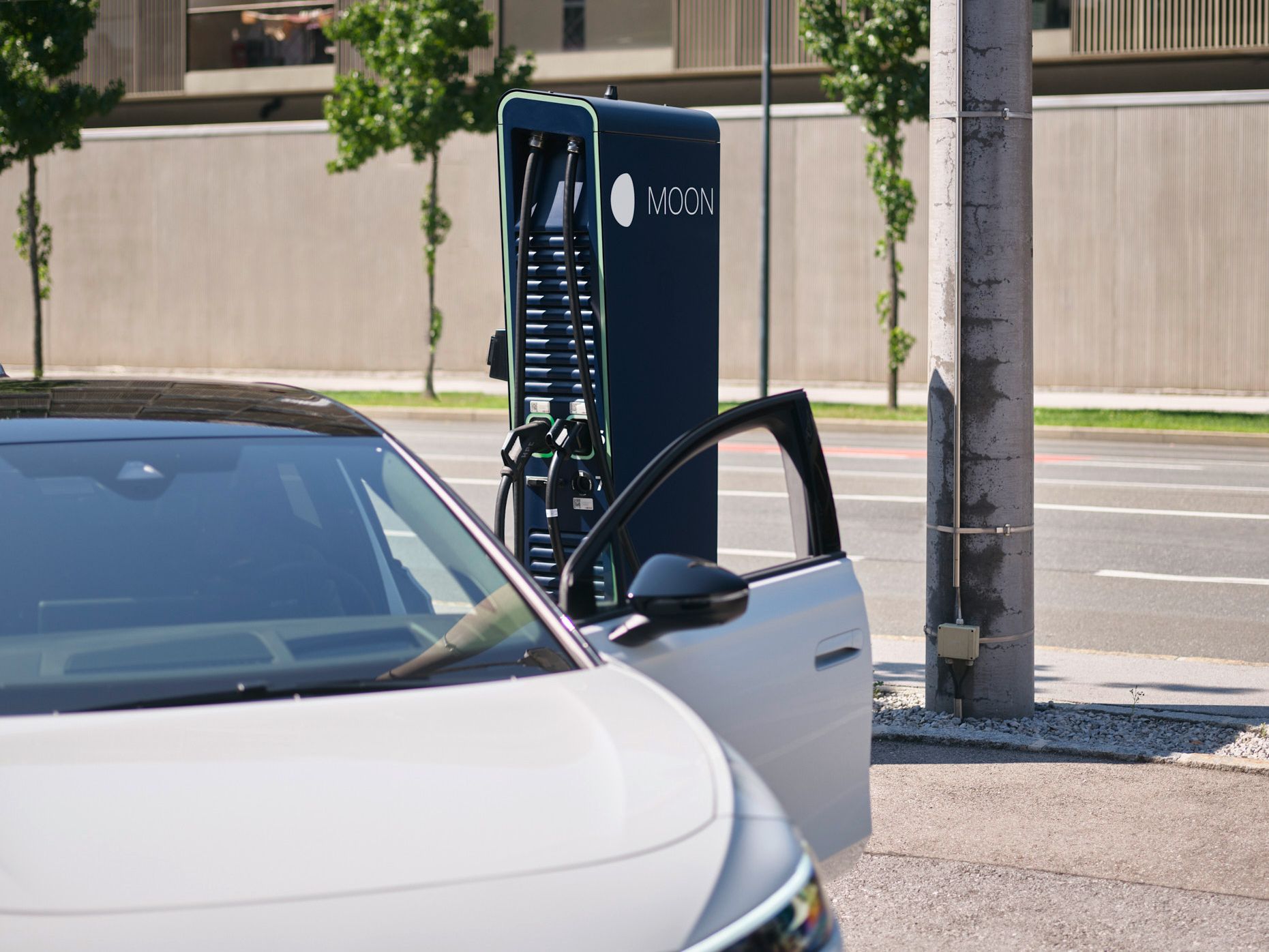 E-Auto steht vor einer Schnellladestation mit Straße im Hintergrund