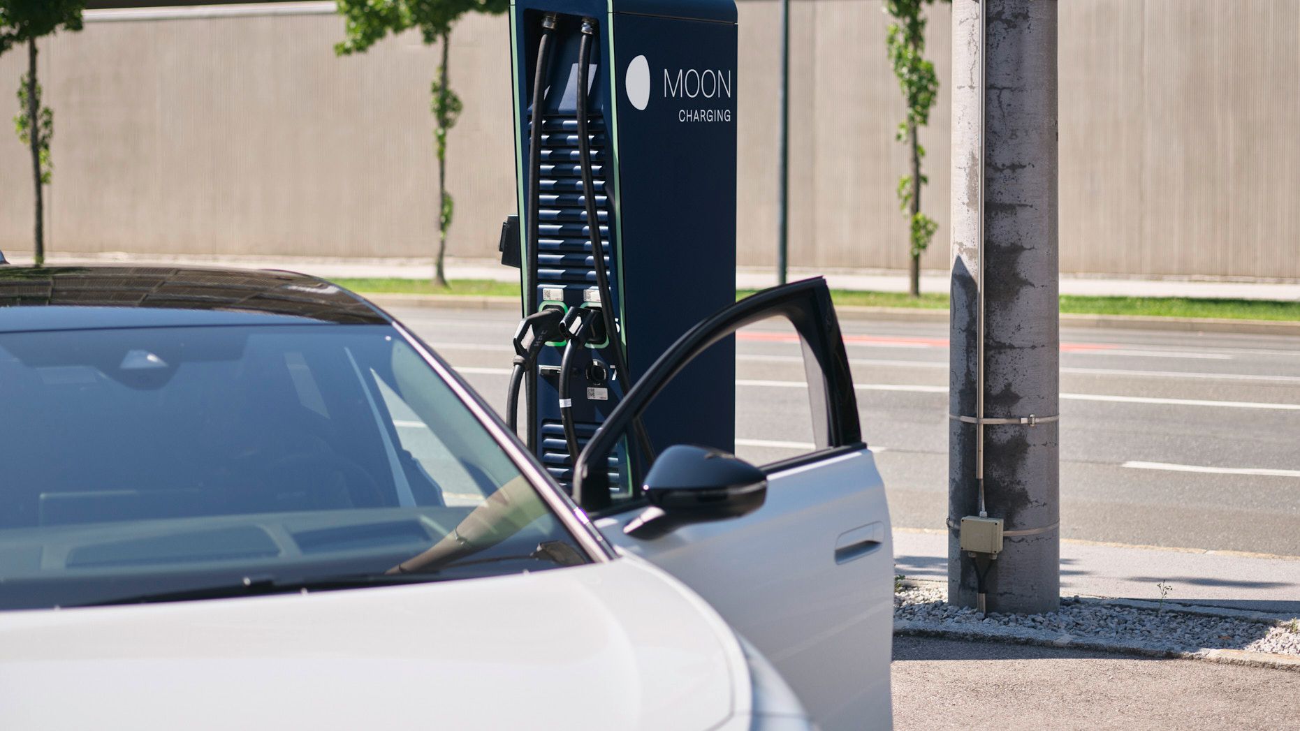 Auto steht vor einer Ladestation mit Straße im Hintergrund