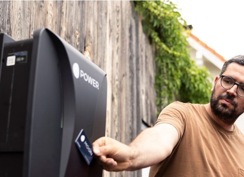 Mann haelt Karte an Wallbox für E-Autos